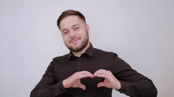 Glada manliga leenden, gör en hjärtform med sina händer. Begreppet kärlek — Stockvideo
