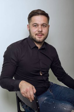 Kendine güvenen, ciddi bir adam. Sandalyeye oturuyor ve dik dik bakıyor..