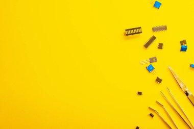 Sarı arka planda cımbız ve elektronik parçalar