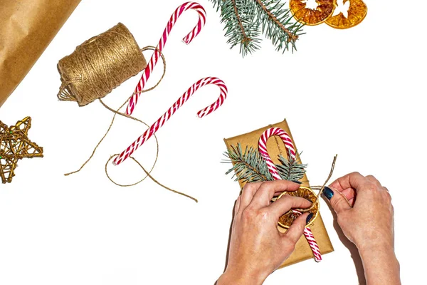 Dişi eller yeni yıl hediyesini beyaz ahşap bir masaya sarıyorlar..