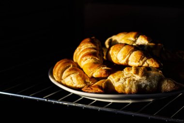 Sabahın erken saatlerinde, güneş ışınları kruvasanların üzerine düşer. Taze kokulu Fransız kahvaltısı..
