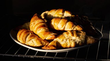Sabahın erken saatlerinde, güneş ışınları kruvasanların üzerine düşer. Taze kokulu Fransız kahvaltısı..