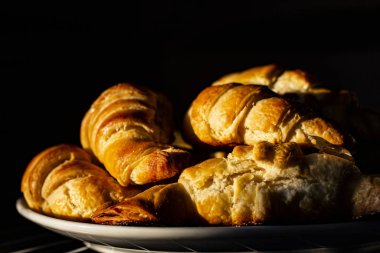 Sabahın erken saatlerinde, güneş ışınları kruvasanların üzerine düşer. Taze kokulu Fransız kahvaltısı..