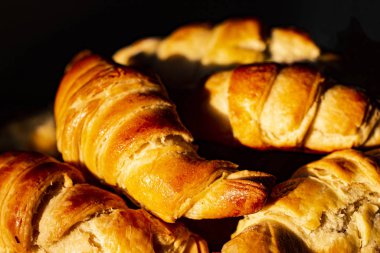 Sabahın erken saatlerinde, güneş ışınları kruvasanların üzerine düşer. Taze kokulu Fransız kahvaltısı..