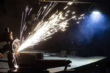 Açı öğütücü metali parlatır ve yıpratıcı tekerlekten kıvılcımlar saçar..