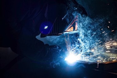 Tamamen karanlıkta maskeli bir kaynakçı metali kaynaklıyor..