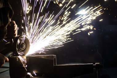 Açı öğütücü metali parlatır ve yıpratıcı tekerlekten kıvılcımlar saçar..