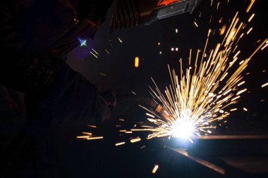 Büyük miktarda duman ve kıvılcım oluşumu ile karanlıkta metal kaynaklama işlemi.