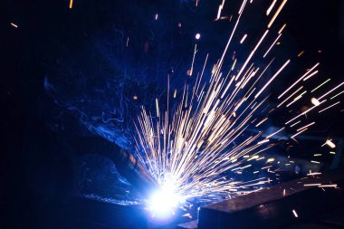 Büyük miktarda duman ve kıvılcım oluşumu ile karanlıkta metal kaynaklama işlemi.