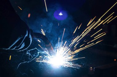 Büyük miktarda duman ve kıvılcım oluşumu ile karanlıkta metal kaynaklama işlemi.