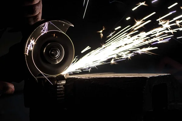 Açı öğütücü metali parlatır ve yıpratıcı tekerlekten kıvılcımlar saçar..