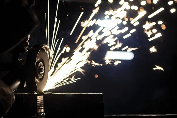 Açı öğütücü metali parlatır ve yıpratıcı tekerlekten kıvılcımlar saçar..