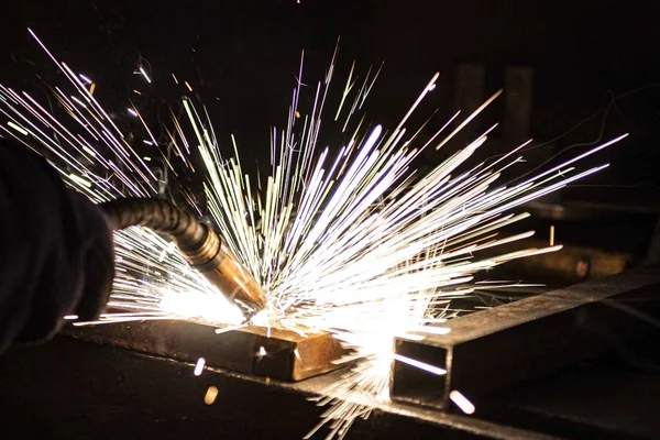 Büyük miktarda duman ve kıvılcım oluşumu ile karanlıkta metal kaynaklama işlemi.