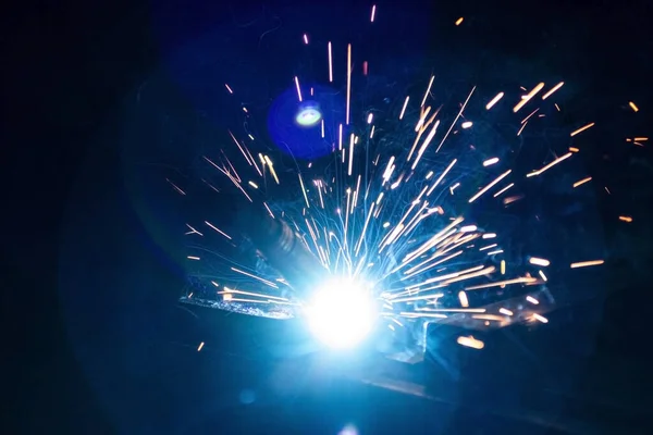 Büyük miktarda duman ve kıvılcım oluşumu ile karanlıkta metal kaynaklama işlemi.