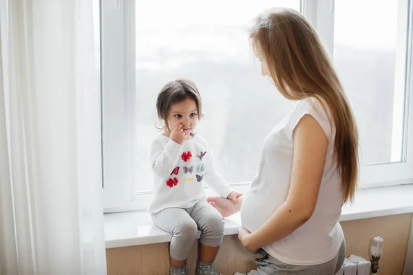 Een Zwangere Moeder Staat Naast Het Raam Met Haar Dochtertje — Stockfoto