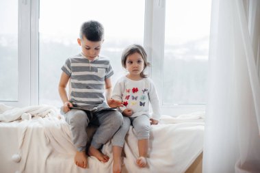 Erkek ve kız kardeş pencere kenarında oturuyorlar ve kitap okuyorlar. Mutluluk, aile