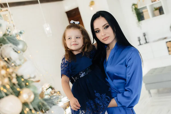 Mom and daughter celebrate and play near the Christmas tree at Christmas. Holiday.