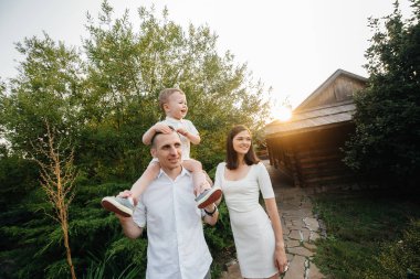Oğulları gün batımında parkta yürüyen mutlu bir aile. Mutluluk. Aşk