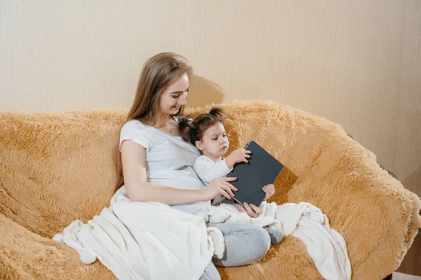 Una Madre Incinta Seduta Sul Divano Con Sua Bambina Gioca — Foto Stock