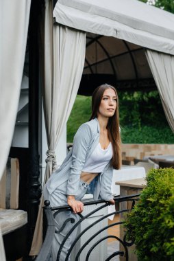 Güzel bir genç kız güzel bir evin verandasında duruyor..