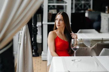 Güzel bir genç kız güzel bir evin verandasında oturur ve şarap içer. Tatil.