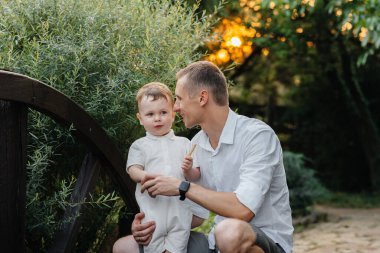 Baba ve oğul gün batımında parkta yürüyorlar. Mutluluk. Aşk