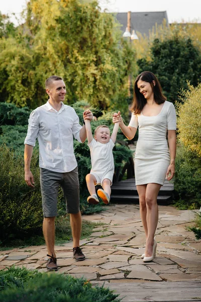 Oğulları gün batımında parkta yürüyen mutlu bir aile. Mutluluk. Aşk