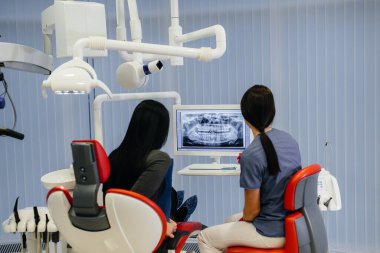 Diş hekimi hastanın dişlerinin bir resmini gösterir ve gerekli tedaviyi söyler. Diş sağlığı, sağlık.