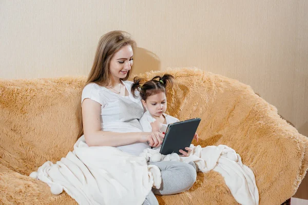 一个怀孕的母亲和她的小女儿坐在沙发上玩小玩意 — 图库照片