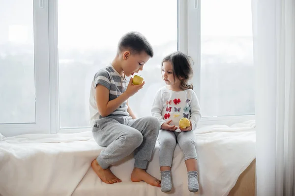 Irmão Irmã Estão Sentados Peitoril Janela Brincando Comendo Maçãs Felicidade — Fotografia de Stock
