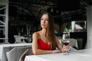 Güzel bir genç kız güzel bir evin verandasında oturur ve şarap içer. Tatil.