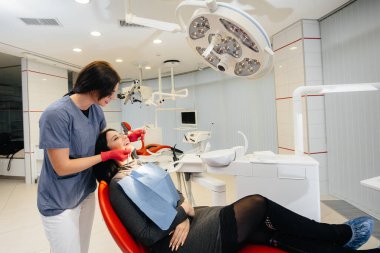 Genç bir doktor hastasının dişlerini tedavi eder. Dişçilik