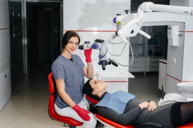 Dişçi mikroskoptan bakar ve hastayı ameliyat eder.