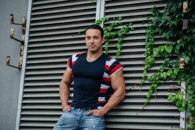 Sportif bir adam gri bir duvarın yanında duruyor. Yaşam biçimi