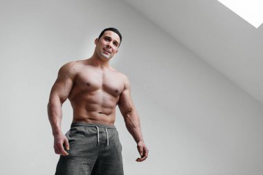 Beyaz arka planda gülümseyen sportif, seksi bir sporcu. Fitness