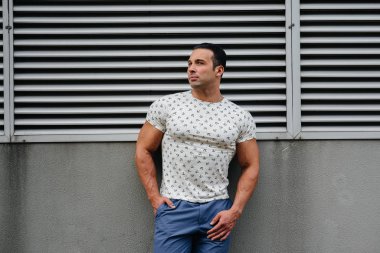 Sportif bir adam gri bir duvarın yanında duruyor. Yaşam biçimi