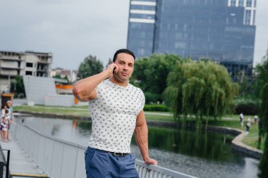 Sporcu çocuk ayakta duruyor ve telefonda konuşuyor. Yaşam biçimi