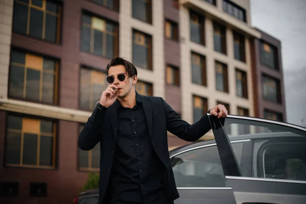 スタイリッシュなビジネスマンは高級車の近くで葉巻を吸う ファッション ビジネス — ストック写真