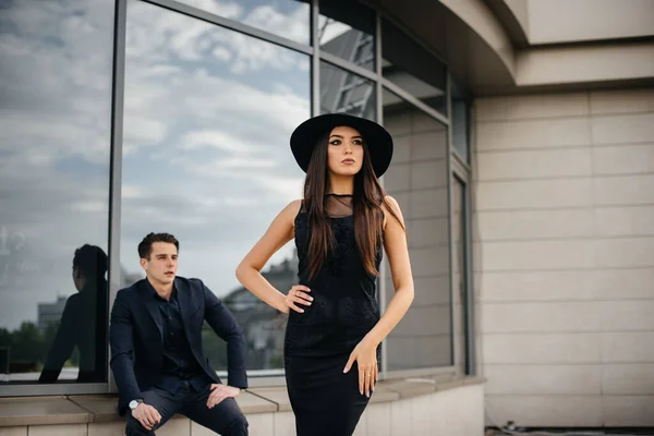 日落时 一对穿着黑色衣服和眼镜的漂亮时髦的年轻人站在一幢办公楼的后面 时尚与时尚 — 图库照片