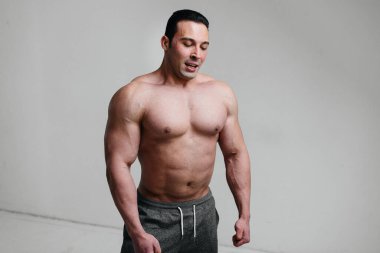 Beyaz arka planda üstsüz poz veren seksi bir sporcu. Fitness