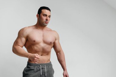 Beyaz arka planda üstsüz poz veren seksi bir sporcu. Fitness