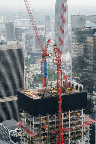 Construction of a modern high-rise skyscraper with cranes in the center of the metropolis. Construction