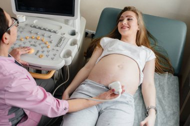 Hamile bir kız klinikte karnının ultrasonuna giriyor. Tıbbi muayene