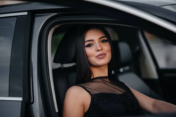 黒のドレスでビジネスクラスの車の中に座ってスタイリッシュな若い女の子 ファッション スタイル — ストック写真