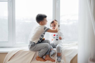 Erkek ve kız kardeş pencere kenarında oturuyor ve elma yiyorlar. Mutluluk