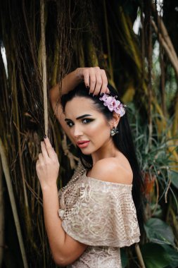 Genç ve güzel bir esmer, sık orman ve yağmur ormanları arasında poz veriyor. Spa