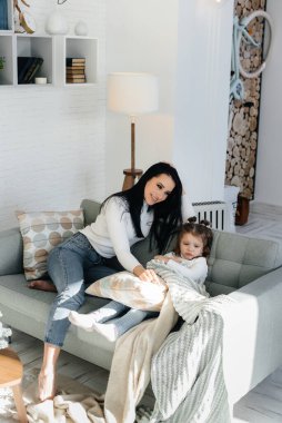 Anne ve kızları kanepede oynuyorlar. Bir aile. Mutluluk.