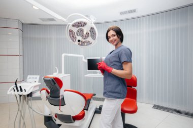 Dişçi dişçi koltuğunun yanında duruyor.