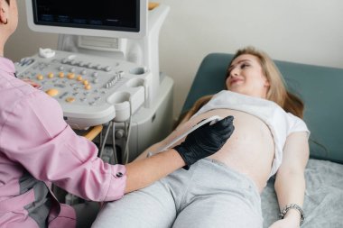 Hamile bir kız klinikte karnının ultrasonuna giriyor. Tıbbi muayene
