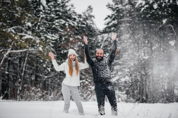 Couple playing with snow in the forest